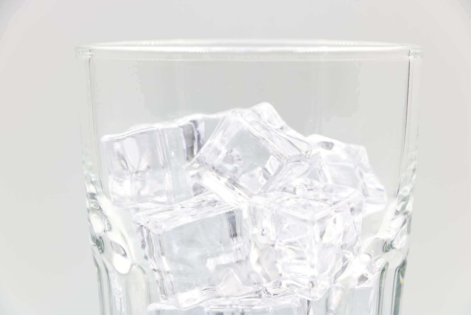 Clear ice cubes in a glass against a pale background